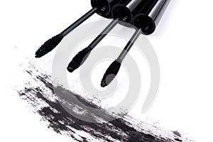 Brushes wands and smudged mascara on white background