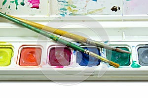Brushes in water color box on white background