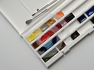 brushes and watercolor paints on a white background