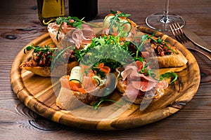 Brushetta set for wine. Variety of small sandwiches with prosciutto, parmesan cheese served on rustic wooden board