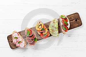Brushetta or traditional spanish tapas. Appetizers italian antipasti snacks set on wooden board. Top view and flat lay with space