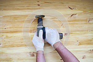 The brushing process of wooden plank. Male hand is holding brushing machine electrical rotating with brush metal disk sanding a