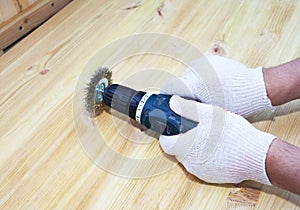 The brushing process of wooden plank. Male hand is holding brushing machine electrical rotating with brush metal disk sanding a