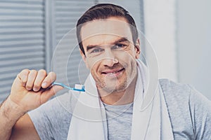 Pleasant man smiling broadly brushing his teeth photo