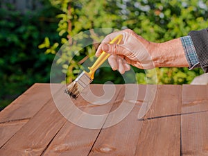 Brushing wood with brush. Painting and wood maintenance oil-wax.