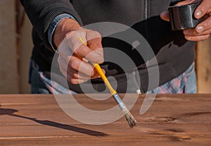 Brushing wood with brush. Painting and wood maintenance oil-wax.