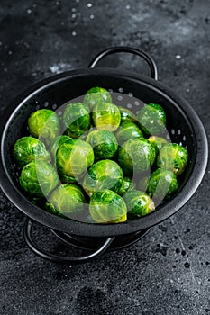Brussels sprouts green cabbage in colander. Black background. Top view