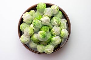 Brussels sprouts its leaves lie on the table and in a wooden bowl