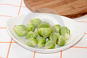 Brussels sprouts in a white bowl on a kitchen table cloth
