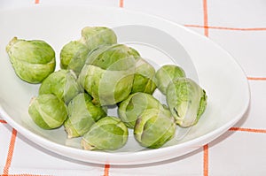 Brussels sprouts in a white bowl on a kitchen table cloth