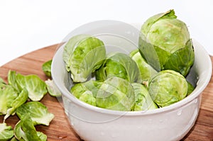 Brussels sprouts in a white bowl on a kitchen wooden board