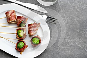 Brussels sprouts wrapped in bacon served on table, flat lay. Space for text