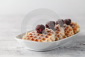 Brussels waffles with blackberries on white plate