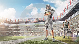 Brutal an American football player stands at stadium during daytime. Arms-standing. Sports emotions