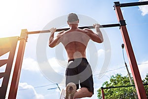 Brutal athletic man making pull-up exercises on a crossbar.