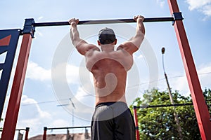 Brutal athletic man making pull-up exercises on a crossbar.