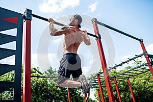 Brutal athletic man making pull-up exercises on a crossbar.