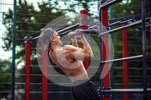 Brutal athletic man making pull-up exercises on a crossbar.