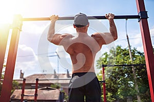 Brutal athletic man making pull-up exercises on a crossbar.