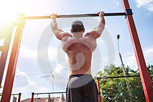 Brutal athletic man making pull-up exercises on a crossbar.