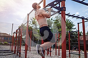 Brutal athletic man making pull-up exercises on a crossbar.