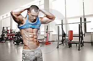 Brutal athletic man taking shirt off on the gym photo