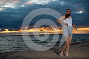 A brutal bald man posing on the beach at sunset parody glamorous chick