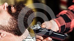 Brutal bearded guy getting beard haircut by hairdresser at barbershop, close up. Getting perfect shape