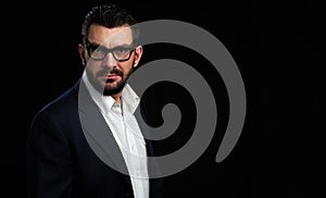 Brutal bearded man wearing spectacles. Black background
