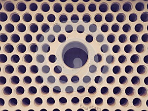 Brutal cement wall with a lot of small close-packed holes with copyspace in the central big hole. Abstract urban background. photo
