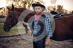 Brutal cowboy poses with horse, wild west