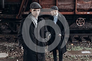 brutal gangsters posing on background of railway carriage. england in 1920s theme. fashionable confident man. atmospheric moments