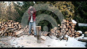 Brutal lumberjack chopping wood in the winter forest