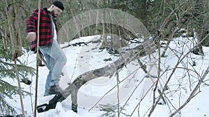 Brutal lumberjack chopping wood in the winter forest