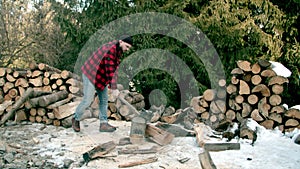 Brutal lumberjack chopping wood in the winter forest