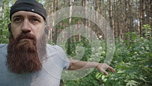 Brutal man with beard in cap goes in for sports outdoor, does warm-up