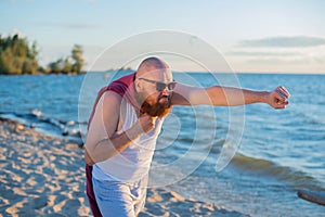A brutal man posing on the beach imitating a flying superhero.