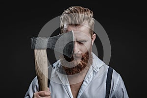 Brutal man in suspenders with ax isolated on black. Mature redhead man with hairstyle. Brutal male fashion style. Male