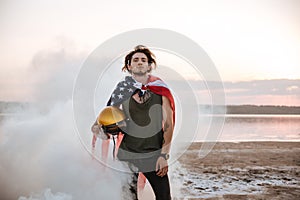 Brutal man wearing usa flag cape posing in white smoke