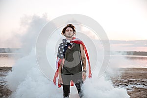 Brutal man wearing usa flag cape posing in white smoke