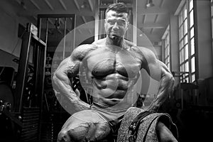 Brutal and muscular strong bodybuilder athletic man pumping up muscles at workout in the gym