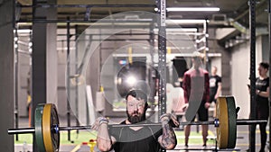 Brutal Strong Man Does Overhead Lift with Barbell Athletic Training in Gym