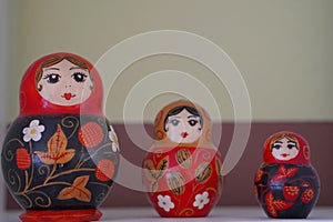 Bryansk, Russia - March 2022: figurines of wooden painted Russian dolls in red sundresses and shawls on a wooden shelf macro