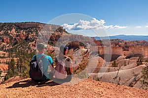 Bryce Canyon - Sitting couple with scenic aerial view from Fairyland hiking trail on massive hoodoo sandstone rock formations