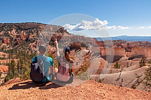 Bryce Canyon - Sitting couple with scenic aerial view from Fairyland hiking trail on massive hoodoo sandstone rock formations