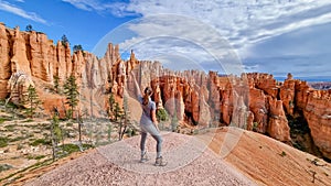 Bryce Canyon - Woman with scenic aerial view of hoodoo sandstone rock formations on Queens Garden trail in Utah, USA