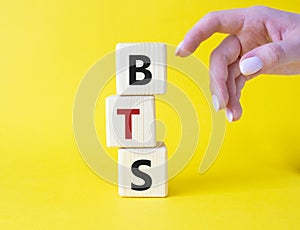 BTS symbol. Wooden cubes with word BTS. Businessman hand Beautiful yellow background. BTS concept. Copy space
