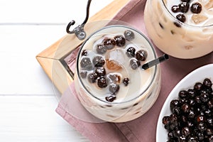 Bubble milk tea with tapioca balls on white wooden table, top view