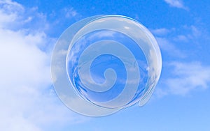 Bubble soap on blue sky with clouds background texture in bright morning. 3d ball, round circle. Transparent glass sphere for