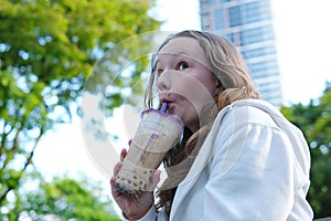 bubble tee Cheerful kid showing like gesture and holding milkshake isolated, banner